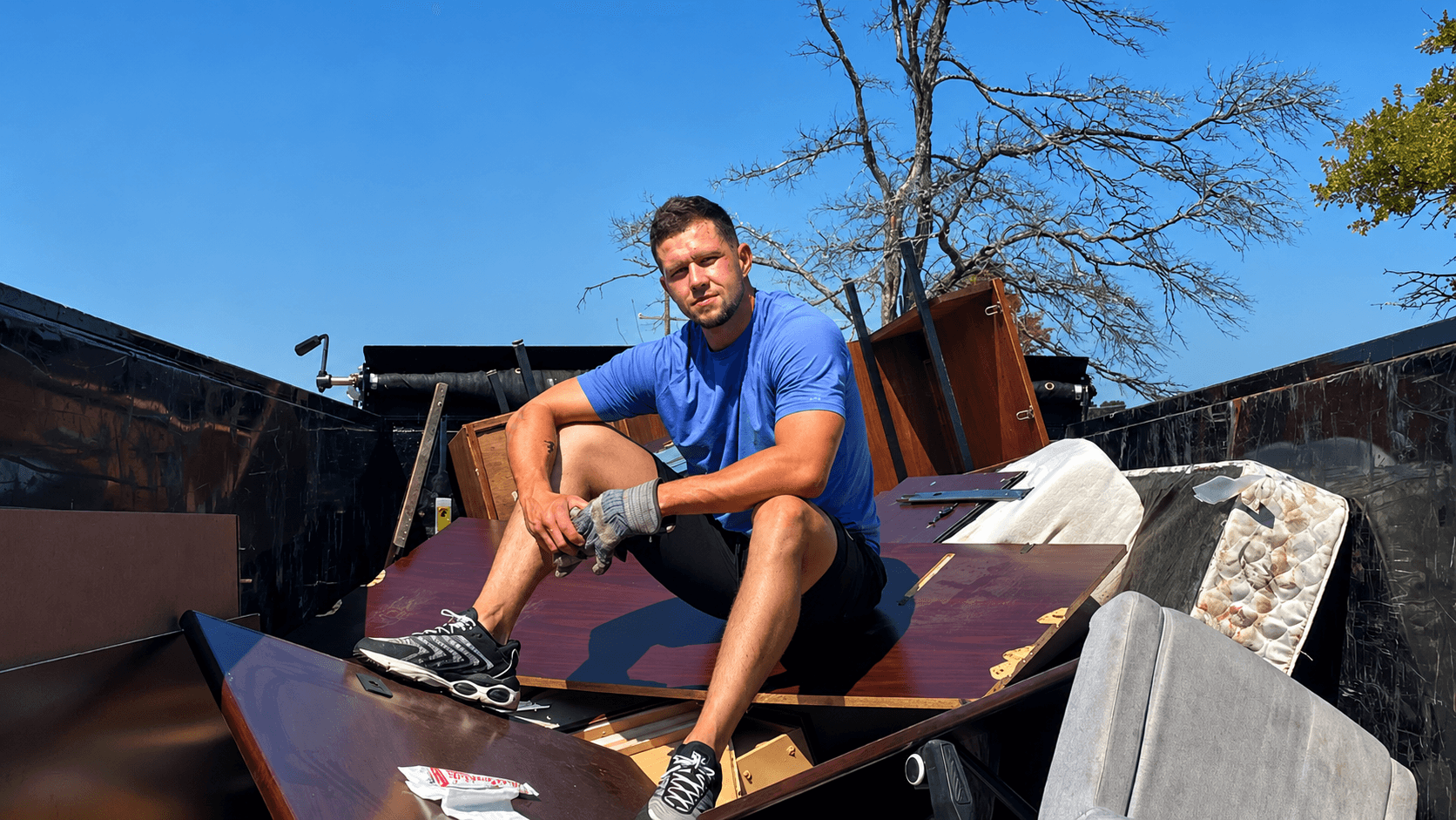 Kane Pro Junk Removal owner on a fully loaded dump trailer after a Rogers, AR cleanout